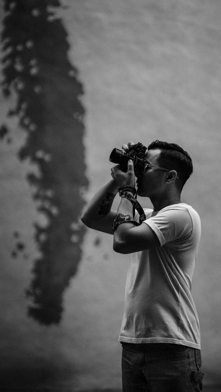 Grayscale Photo of Man Taking Pictures Using a Camera